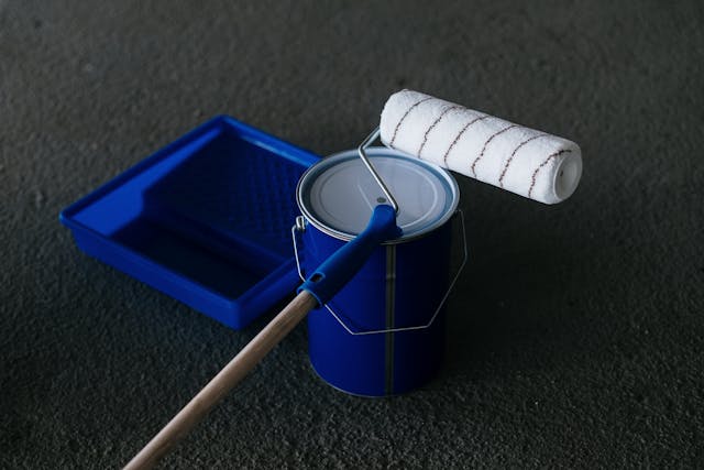 a paint bucket and roller sitting on the floor