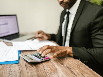 man-in-a-suit-using-a-calculator-at-a-desk-with-financial-documents-and-a-laptop