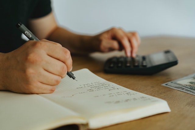 person using a calculator and a notebook to make a budget
